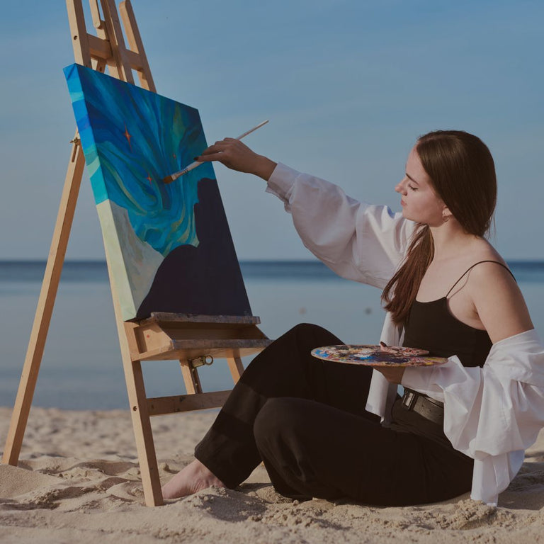 Woman painting on an easel by the beach