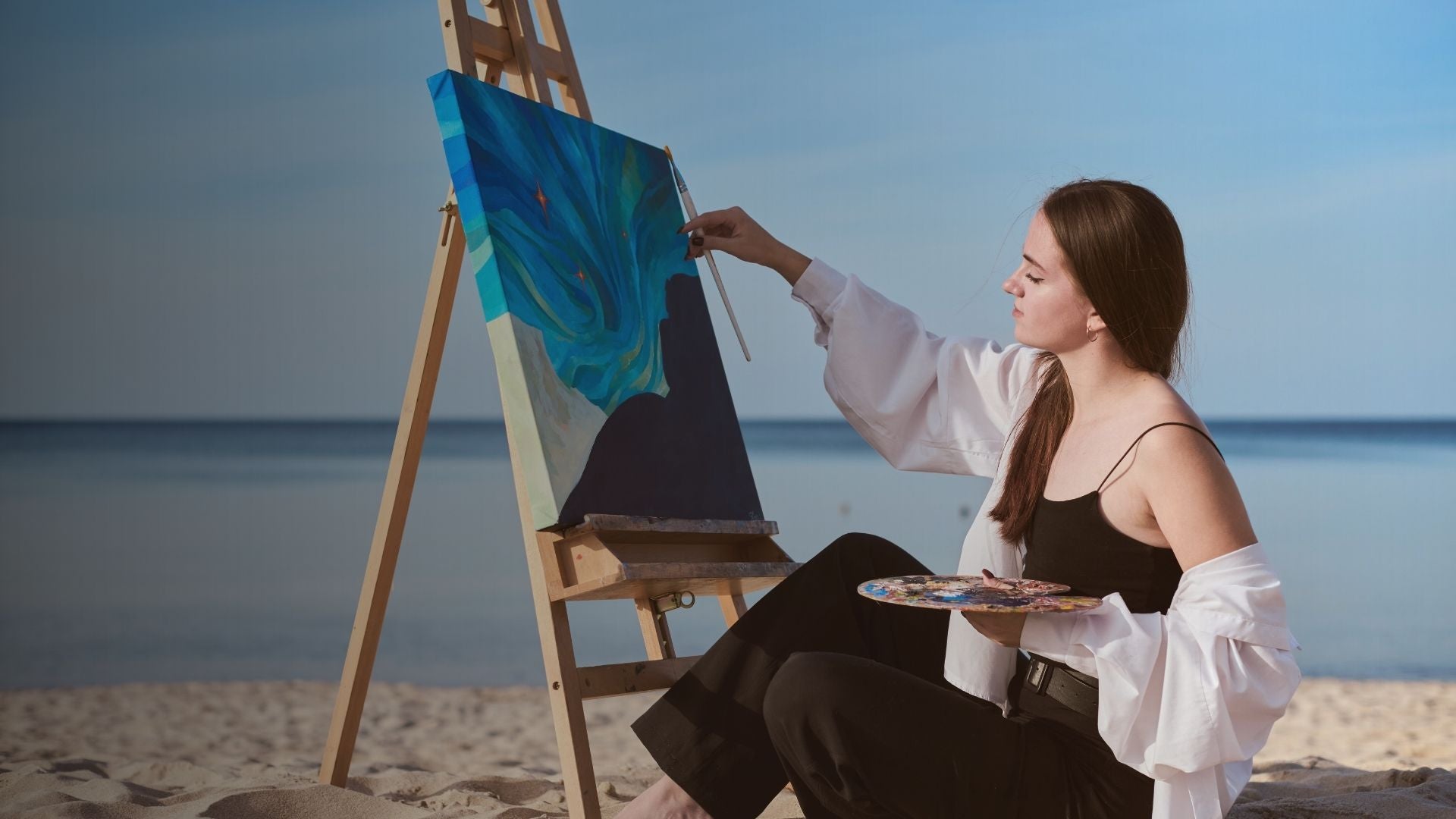 Woman painting on an easel by the beach